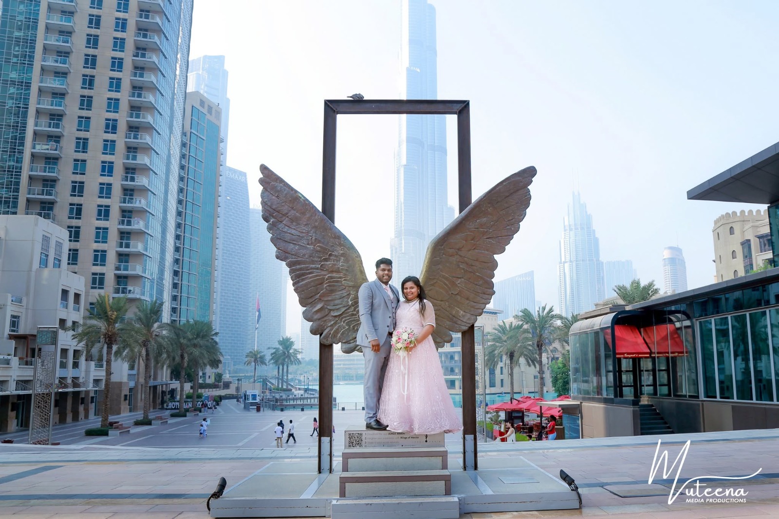 Couple posing inside the Wings of Mexico bronze sculpture at Downtown Dubai with the Burj Khalifa behind — pre-wedding photography Dubai