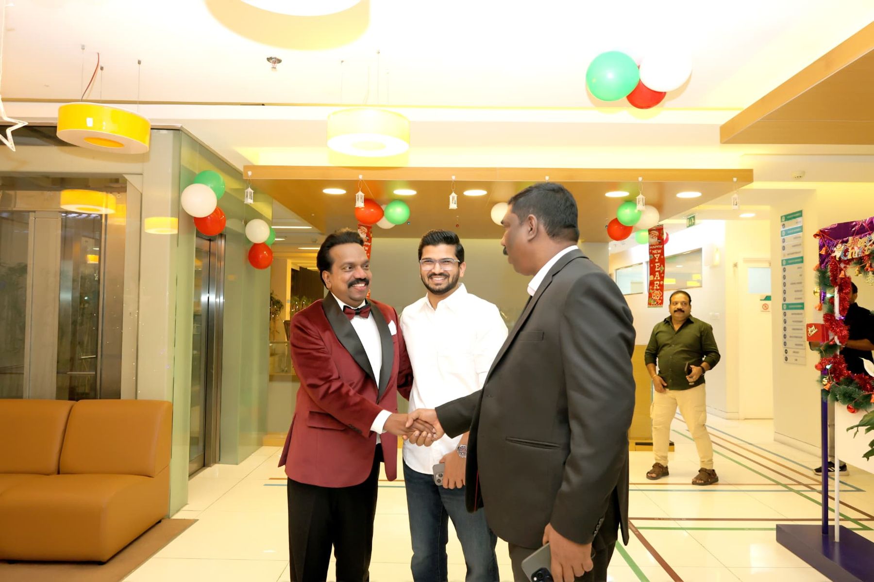 Guests shaking hands and greeting the host at a festive corporate reception in a Dubai hospital lobby decorated with balloons
