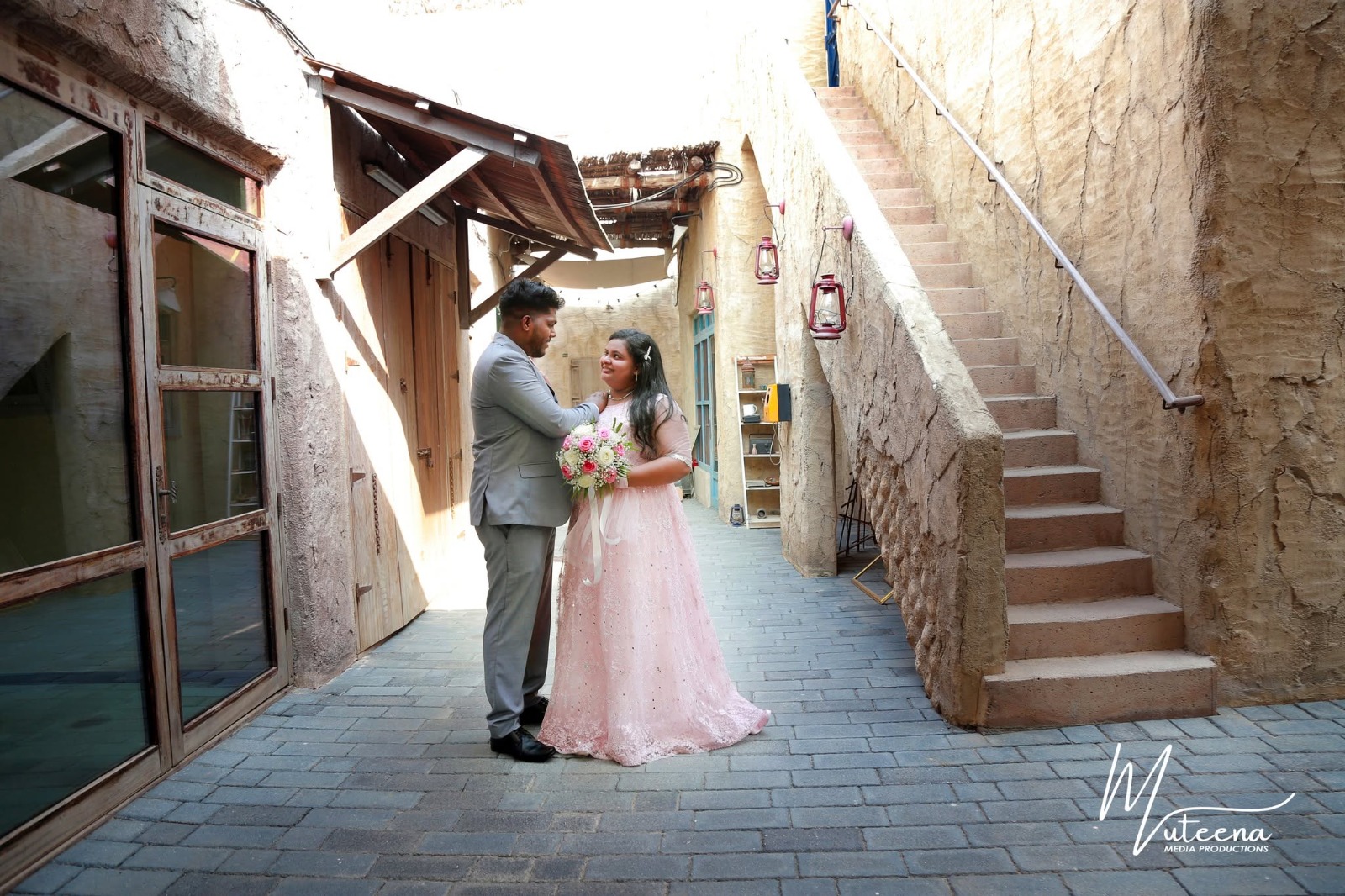 Pre-wedding portrait of a Muslim couple against a Dubai skyline of towers and canal, in coordinated cream and grey — engagement photography by Dar Al Muteena Studio