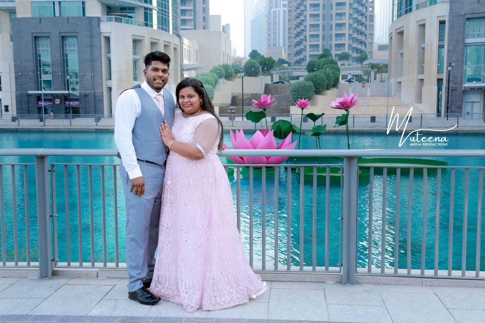 Couple portrait at Downtown Dubai's lotus fountain, woman in a blush pink lace gown and man in a grey three-piece suit — Dubai pre-wedding photography